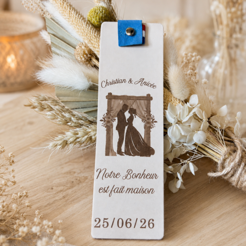 Marque-page personnalisé en cuir tannage végétal posé sur une table de mariage avec décoration florale