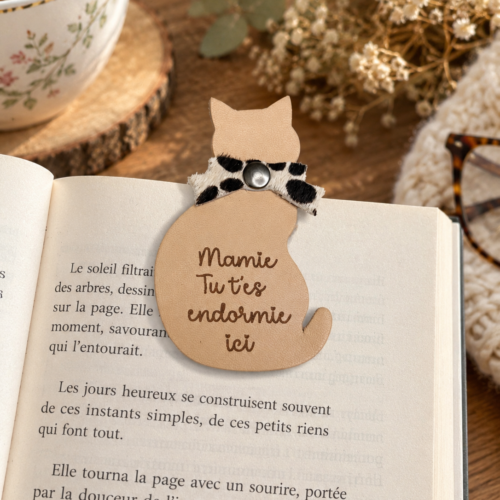 Marque-page magnétique en cuir pour Mamie en forme de chat avec message gravé, posé sur un livre ouvert.
