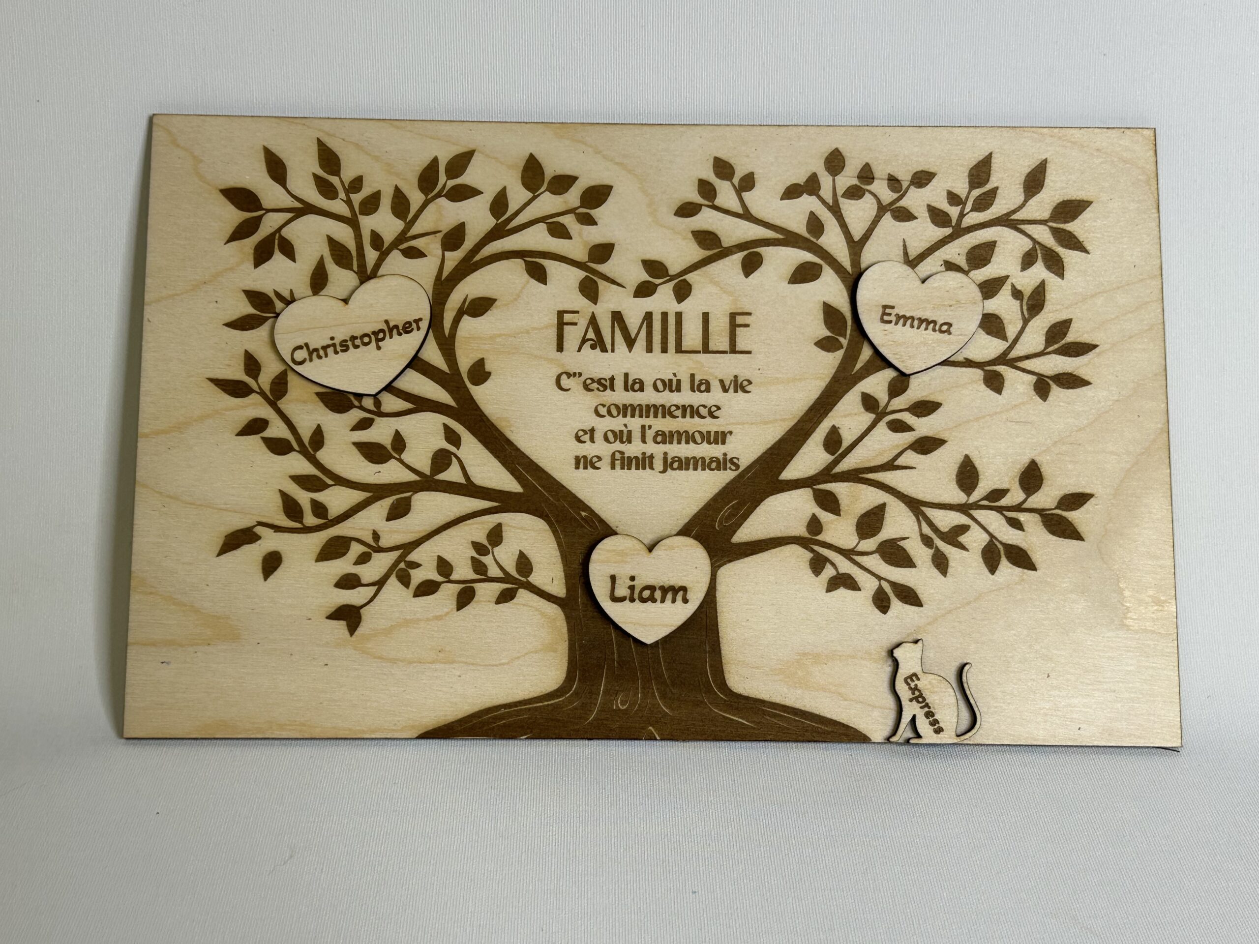 Panneau en bois gravé représentant un arbre de famille personnalisé avec prénoms inscrits dans des cœurs et citation centrale.
