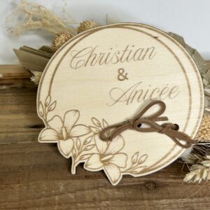 Porte-alliances mariage personnalisé en bois gravé avec prénoms, forme ronde avec décor floral et lien pour maintenir les alliances.