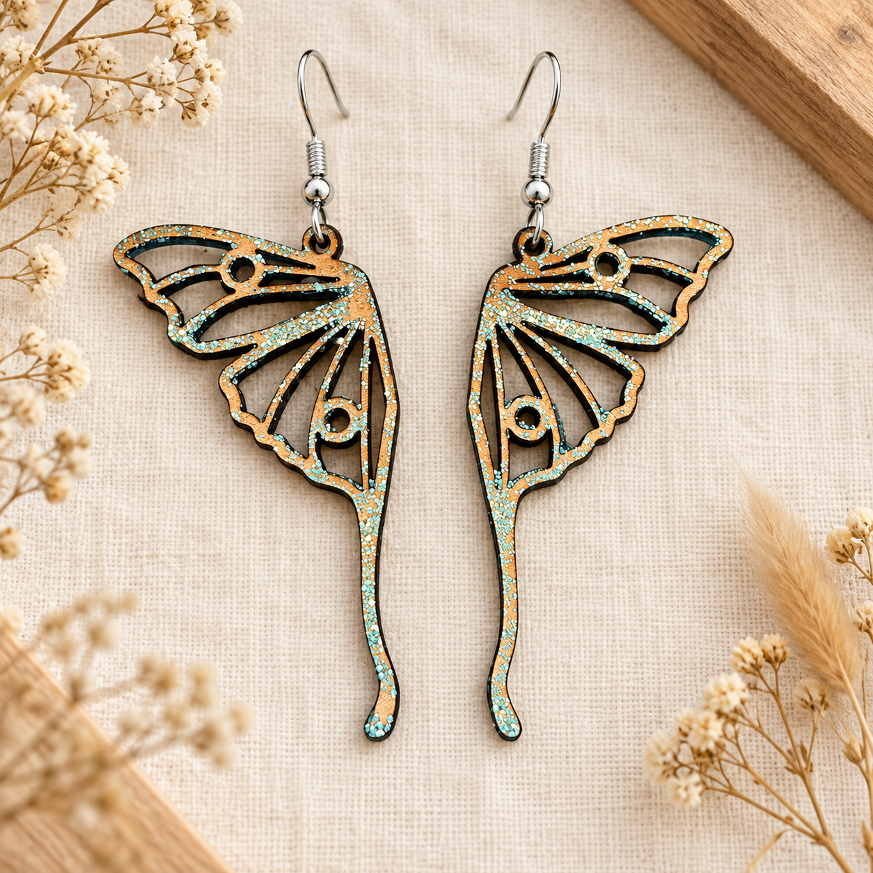 rien qu'un instant Paire de boucles d’oreilles en cuir ajouré en forme de papillon, avec touches de paillettes et montures argentées.